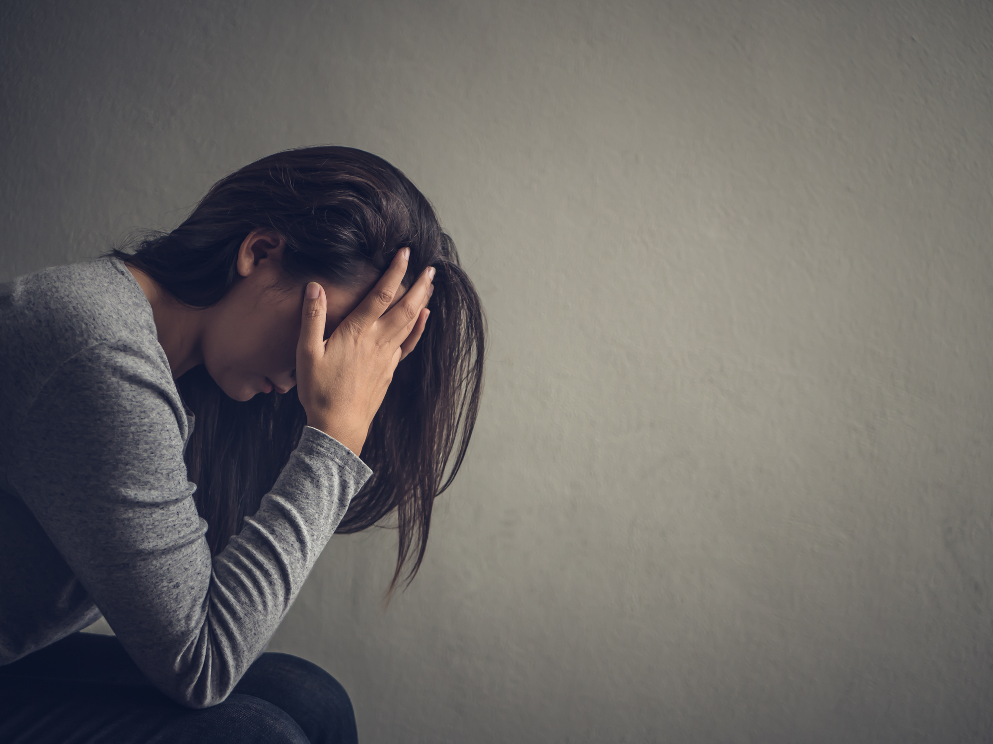Depressed woman sitting on a chair in dark room at home. Lonely fighting tranquilizer addiction