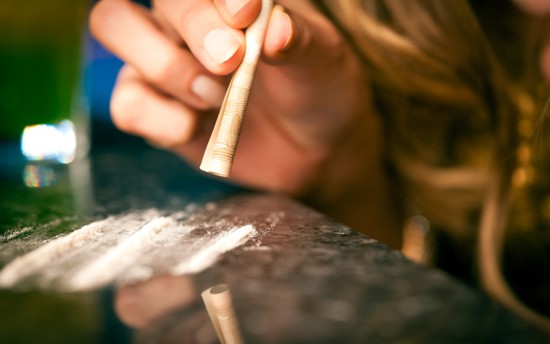 Young woman snorting cocaine with rolled up dollar
